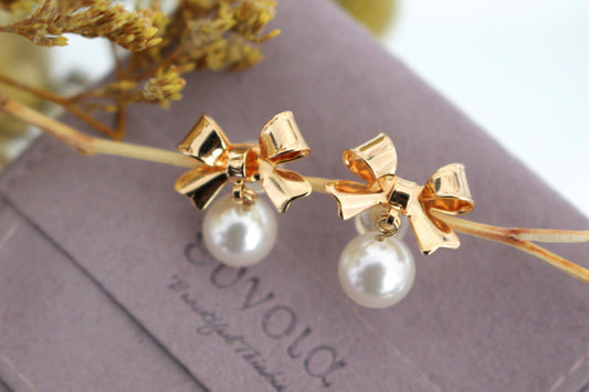 Golden bow and dangling pearl earrings