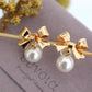 Golden bow and dangling pearl earrings
