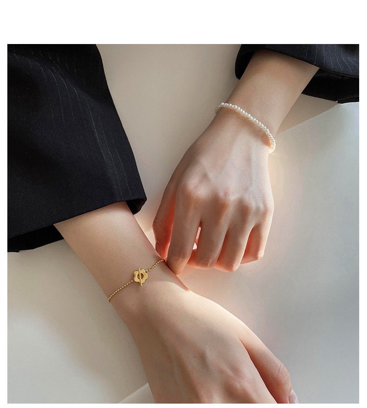 Model's hand wearing gold chain and pearl chain separately 