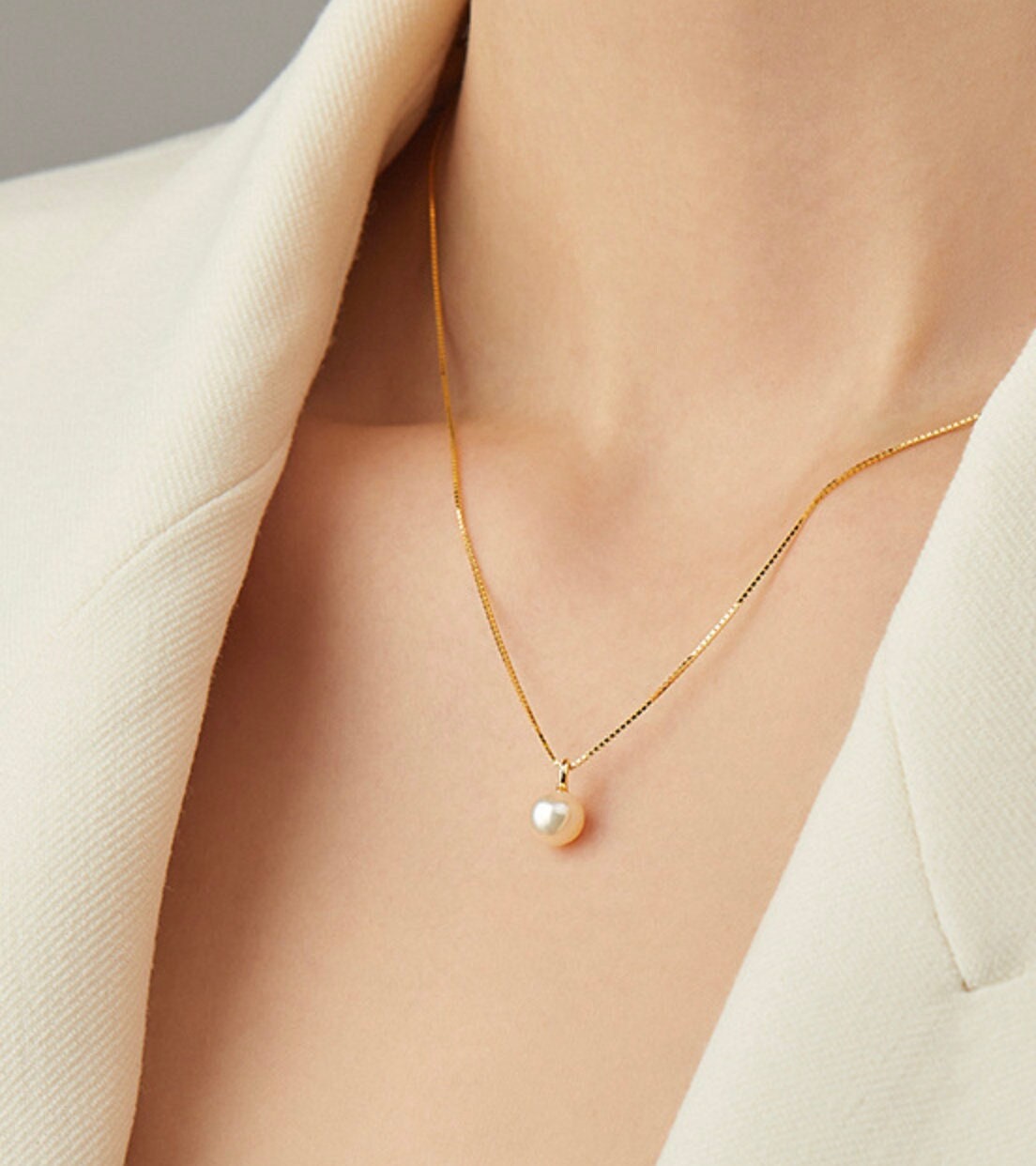 Model wearing single pearl necklace gold chain